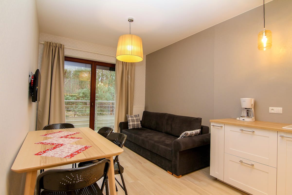 A compact living space with a dining table, a sofa, and a kitchenette.