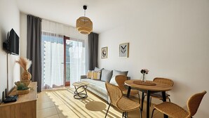 Ein modernes Wohnzimmer mit einer Couch, einem Esstisch, Stühlen und einem Fernseher.