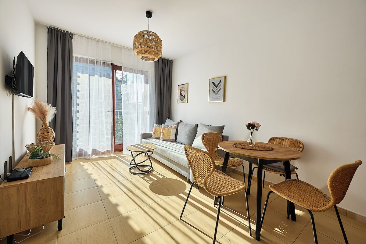 A modern living room with a sofa, dining table, chairs, and a TV.
