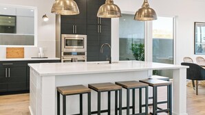 A modern kitchen with a central island, pendant lighting, and a view to the outside. - Ace on the 8th: 2 Private Pools, Sleeps 58! (Washington)