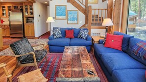Ein großzügiger Wohnbereich mit einem blauen Sofa, Holzböden, einer Treppe und einer Küche mit Holzschränken.