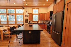 Una cocina con una isla central, armarios de madera y un refrigerador de acero inoxidable.