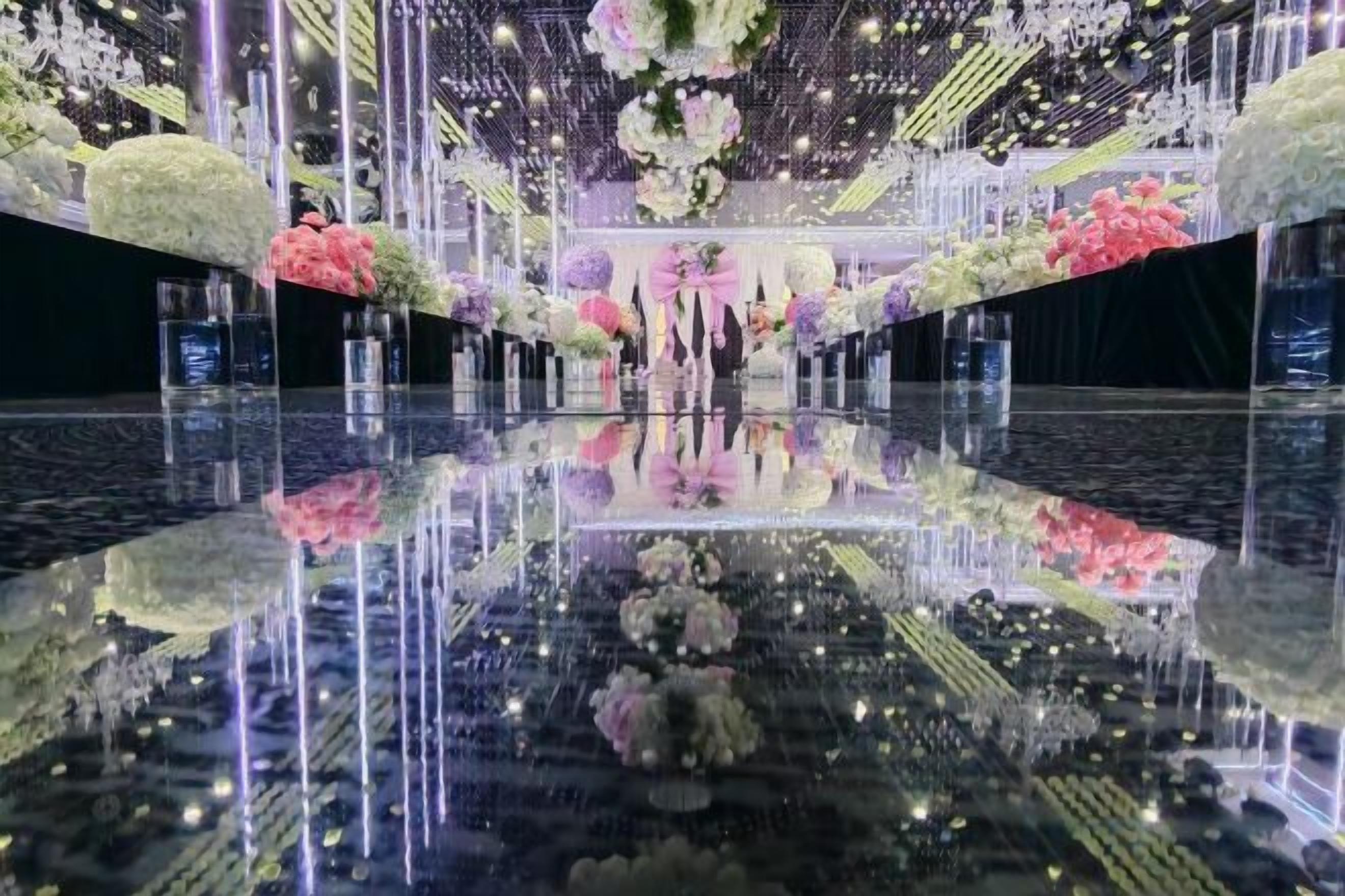Un suelo reflectante con arreglos florales e iluminación vertical.