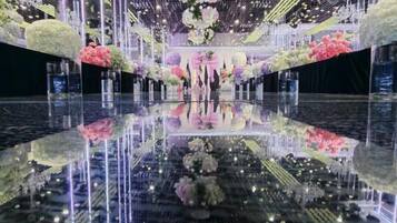 Un suelo reflectante con arreglos florales e iluminación vertical.