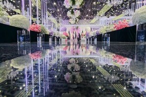 A reflective floor with floral arrangements and vertical light fixtures. - Azalea Garden Hotel (Qianxi)