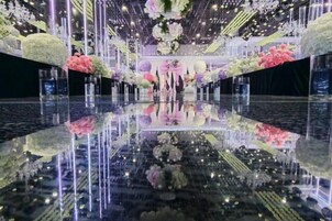 Un suelo reflectante con arreglos florales e iluminación vertical.