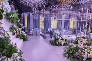 Un restaurante con mesas y sillas redondas, rodeado de arreglos florales y un diseño moderno de techo.