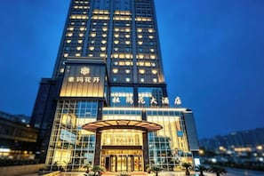 A high-rise hotel with a prominent entrance, large windows, and signage indicating the name. - Azalea Garden Hotel (Qianxi)