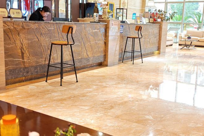 Una zona de recepción con mostrador de mármol, dos taburetes de bar y una recepcionista.