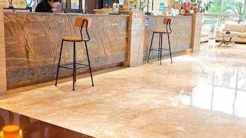 A reception area with a marble counter, two bar stools, and a receptionist.