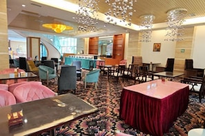 A hotel lobby with a mix of seating arrangements, including sofas and tables, a bar area, and a patterned carpet. - Azalea Garden Hotel (Qianxi)