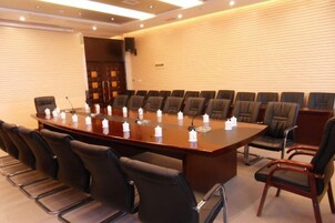 A conference room with a long table, multiple chairs, and microphones.
