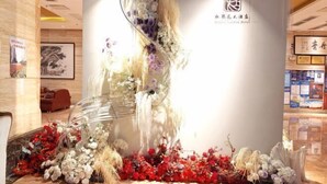 Un hall de hotel con un arreglo floral grande, una recepción y un letrero del Hotel Majestic Garden.