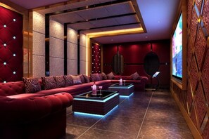 A modern lounge area with a red sofa, a coffee table, and a flat-screen TV. - Azalea Garden Hotel (Qianxi)
