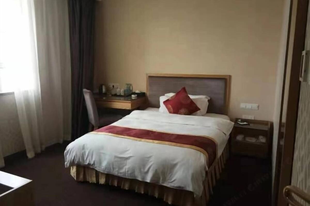 Ett hotellrum med en säng, ett skrivbord och en stol.