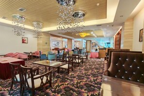 A hotel lobby with a patterned carpet, wooden ceiling, and a mix of seating arrangements including tables and chairs. - Azalea Garden Hotel (Qianxi)