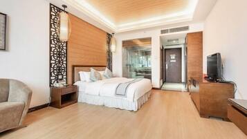 Una habitación de hotel moderna con techo de madera, una cama con ropa blanca, una mesita de noche, un televisor en un mueble de madera y una puerta de vidrio que da a un baño.