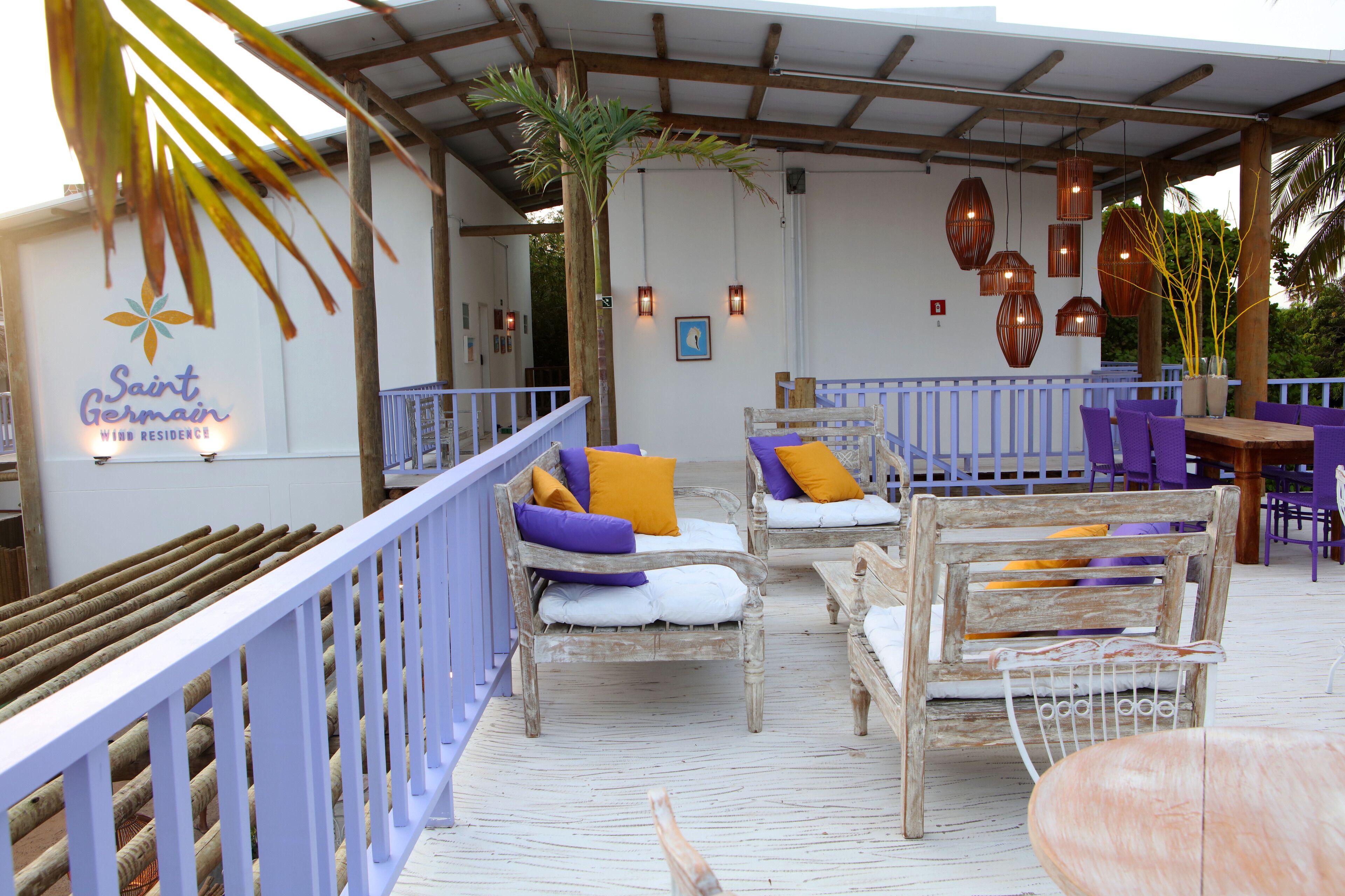 A covered outdoor seating area with wooden furniture and a white railing.
