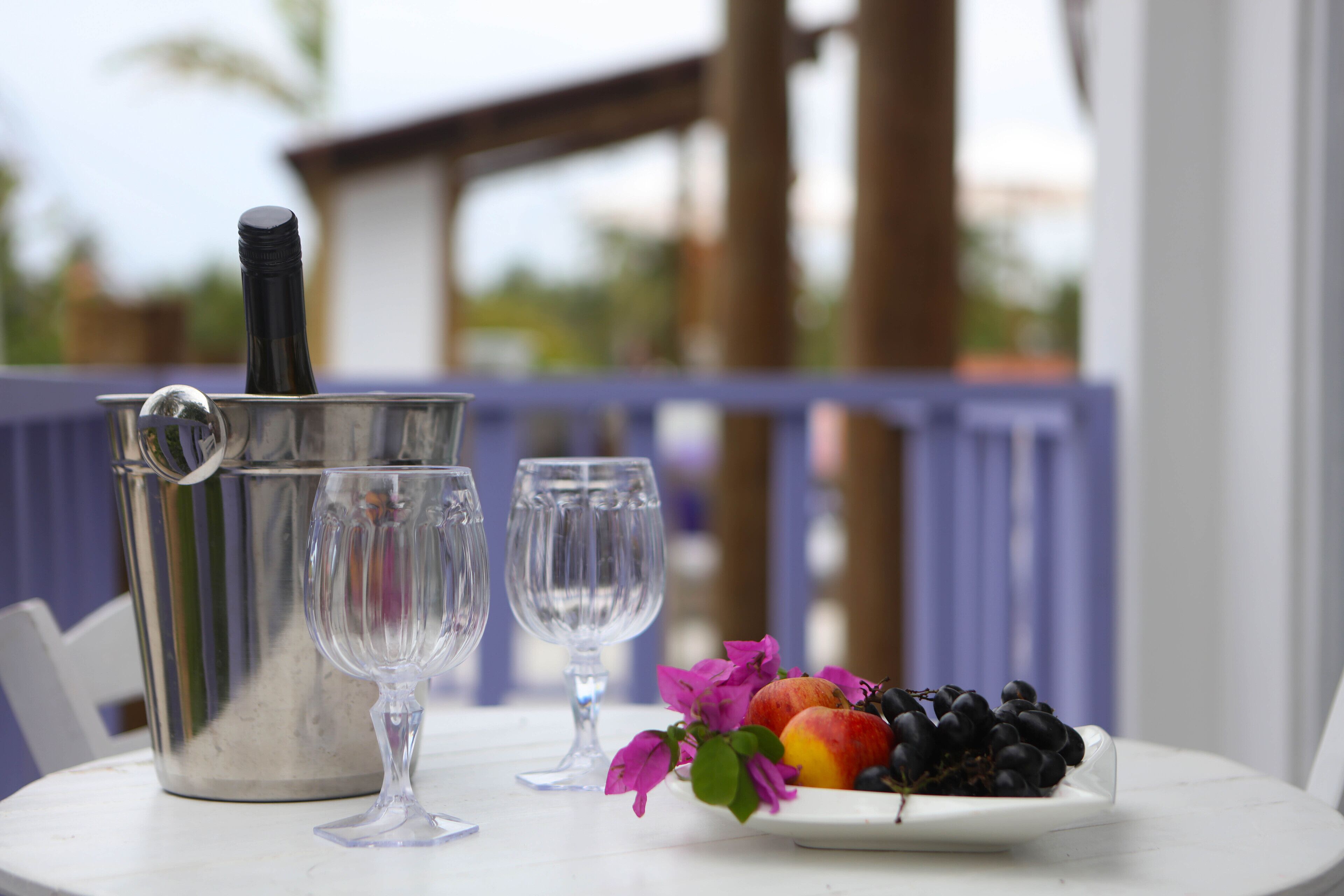 A table with a metal pitcher, two wine glasses, and a plate of fruit.