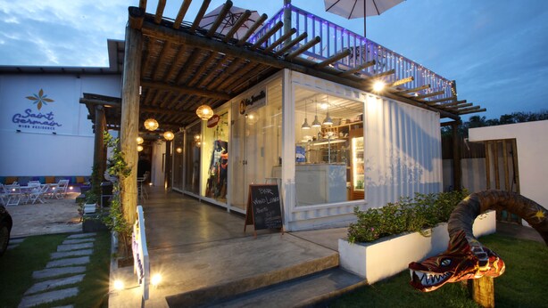 Un restaurante con una pérgola de madera, mesas al aire libre y un letrero que dice 'Bar Wind Longe'.