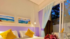 Habitación de hotel con una cama, almohadas, un ramo de flores y una ventana con cortinas.