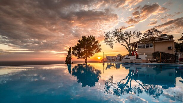 Una piscina infinita que refleja árboles y una puesta de sol.