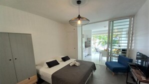 A modern bedroom with a bed, a wardrobe, a desk, a chair, and a TV. - Large, cosy studio with sea view, pool and beach (Le Gosier)
