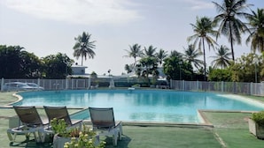 A swimming pool with lounge chairs and palm trees in the background. - Large, cosy studio with sea view, pool and beach (Le Gosier)