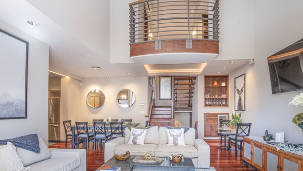 A spacious living area with a high ceiling, a central staircase, and a dining area with multiple chairs. - Airy Townhome in Vail w/ Beautiful Views, Modern Decor, Free bus shuttle. VP7 (Vail)