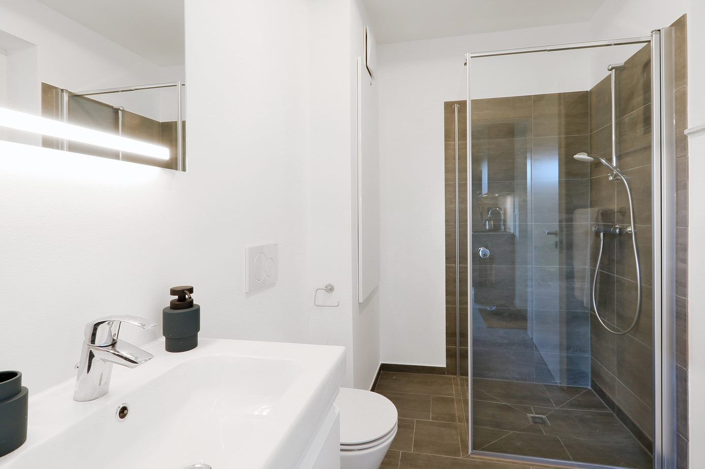 Ein modernes Badezimmer mit einem großen weißen Waschbecken, einer Duschkabine und einer Toilette.