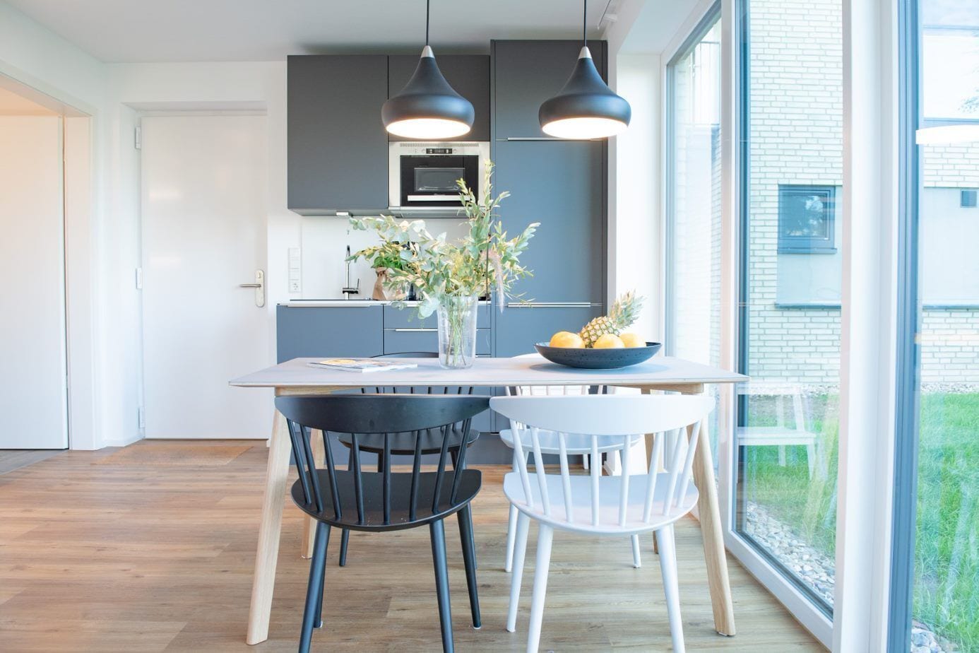 A modern kitchen with dark cabinets, a central island, and pendant lighting.