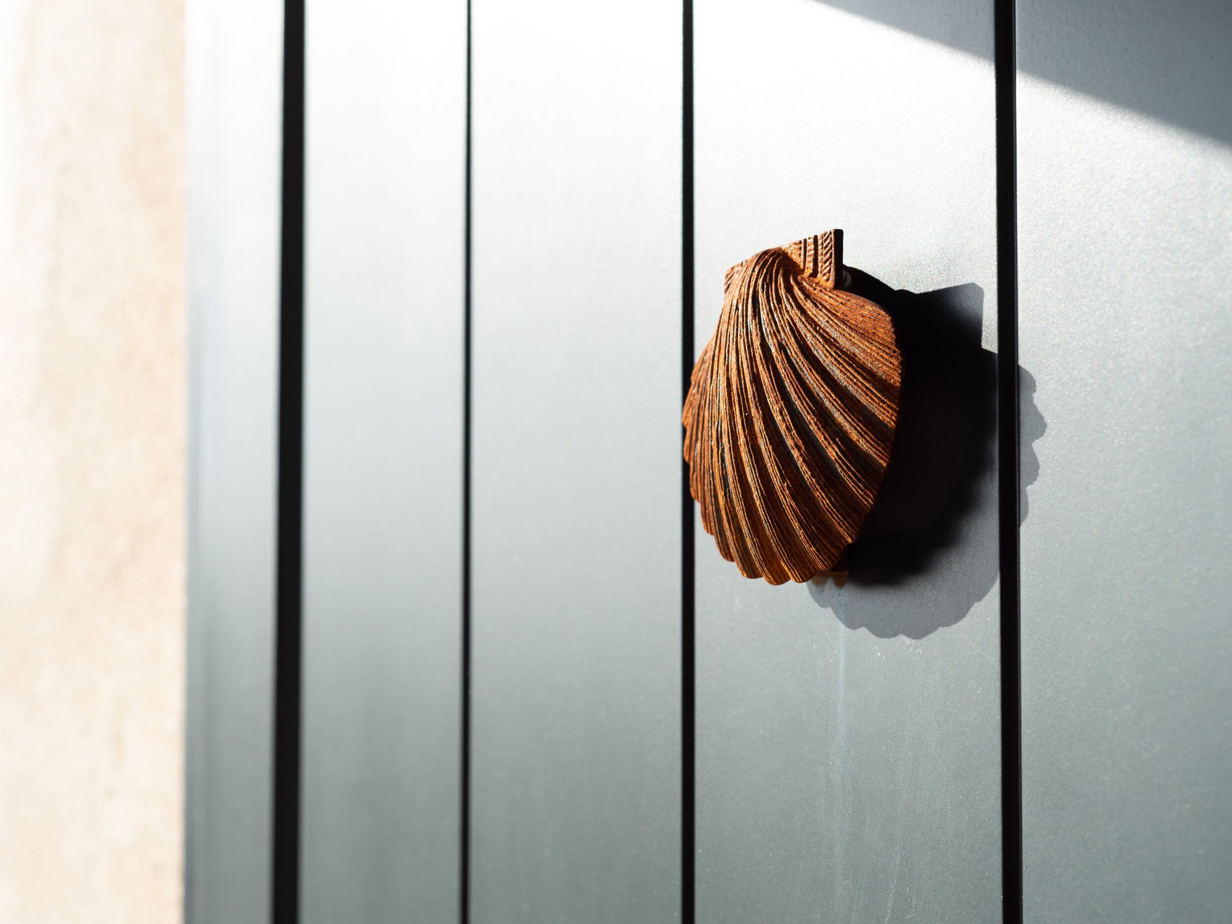 A wooden door with a shell-shaped handle.