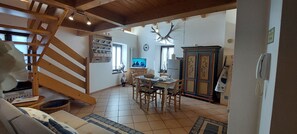 A cozy living room with a wooden staircase, a dining area with a table and chairs, and a kitchen area with a refrigerator and cabinets. - LOFT DELLA PERPETUA
Romantic getaway, relaxation, and nature. Pet-friendly (Montagnaga)