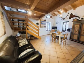 A cozy living room with a black leather sofa, wooden staircase, dining area with a table and chairs, and a kitchen visible in the background. - LOFT DELLA PERPETUA
Romantic getaway, relaxation, and nature. Pet-friendly (Montagnaga)