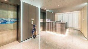 Eine moderne Hotelhalle mit einer Rezeption, einer Vase und einem Bild an der Wand.