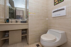 Un baño con inodoro, lavamanos con espejo y un equipo de aire acondicionado de pared.