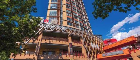 A multi-story hotel with a distinctive curved facade, balconies, and a prominent entrance with a red awning.
