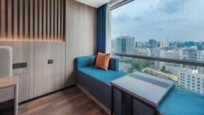 Ein modernes Hotelzimmer mit Blick auf die Stadt, einer Couch, einem kleinen Tisch und einer Wand mit Holzpaneelen.