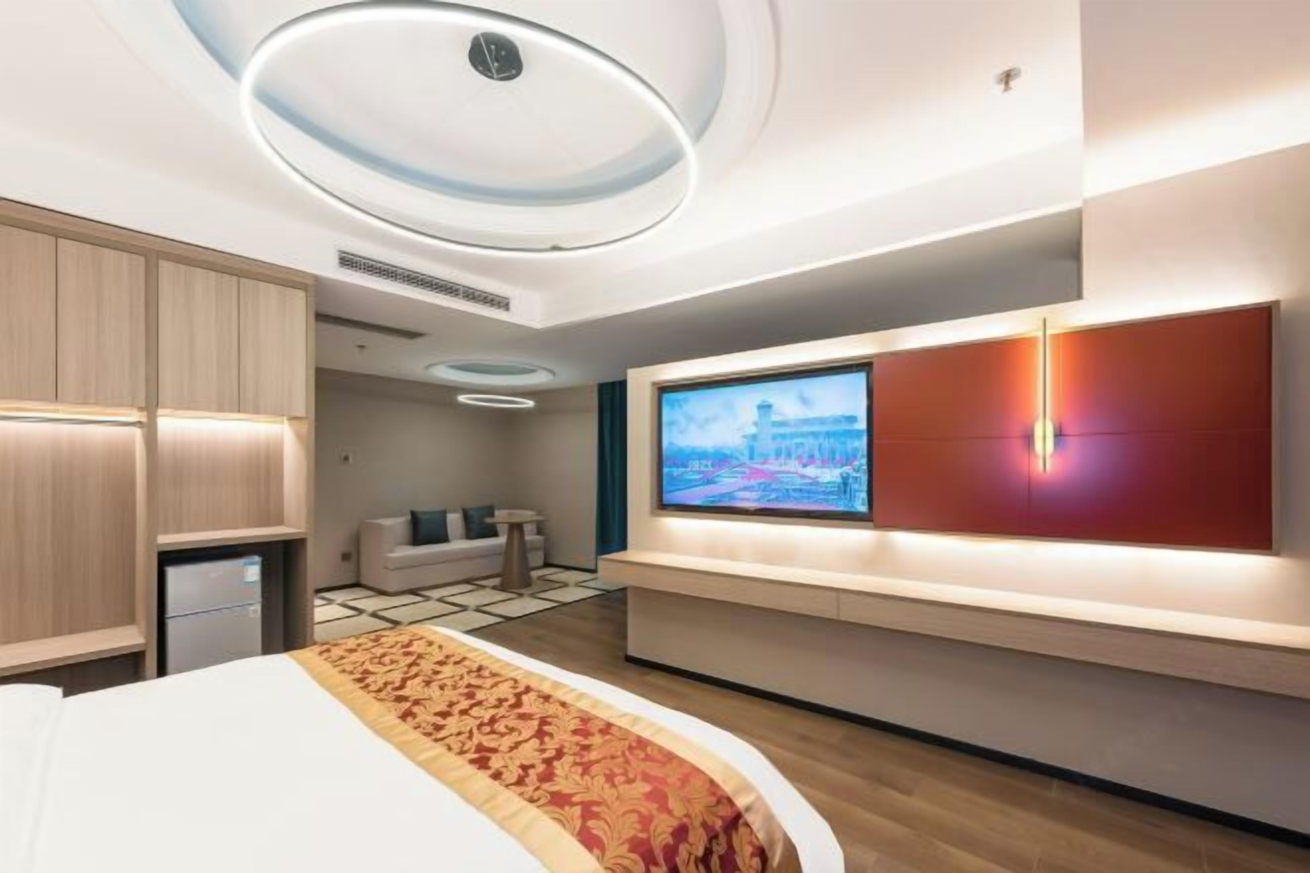 Una habitación de hotel moderna con una cama grande, un televisor montado en la pared y un pequeño rincón de descanso con un sofá y una mesa.