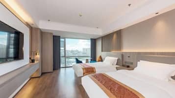 A modern hotel room with two beds, a large window offering a city view, and a balcony.