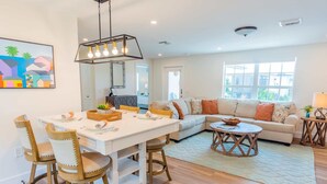A modern living room with a dining area, a sofa set, a coffee table, and a pendant light. - 562 Beachy Keen Cottage| New Pool | Mins 2 Beaches (Naples)