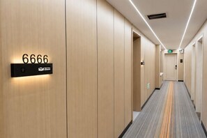 A hotel corridor with a number sign, doors, and a carpeted floor. - Deji Express Hotel (Maqu)
