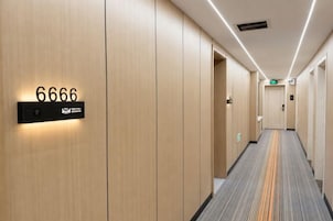 Pasillo de hotel con un cartel de número, puertas y suelo alfombrado.