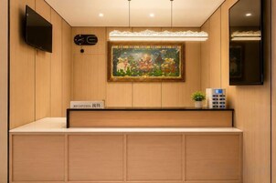 Un mostrador de recepción con un letrero, un cuadro, un reloj y un televisor en la pared.