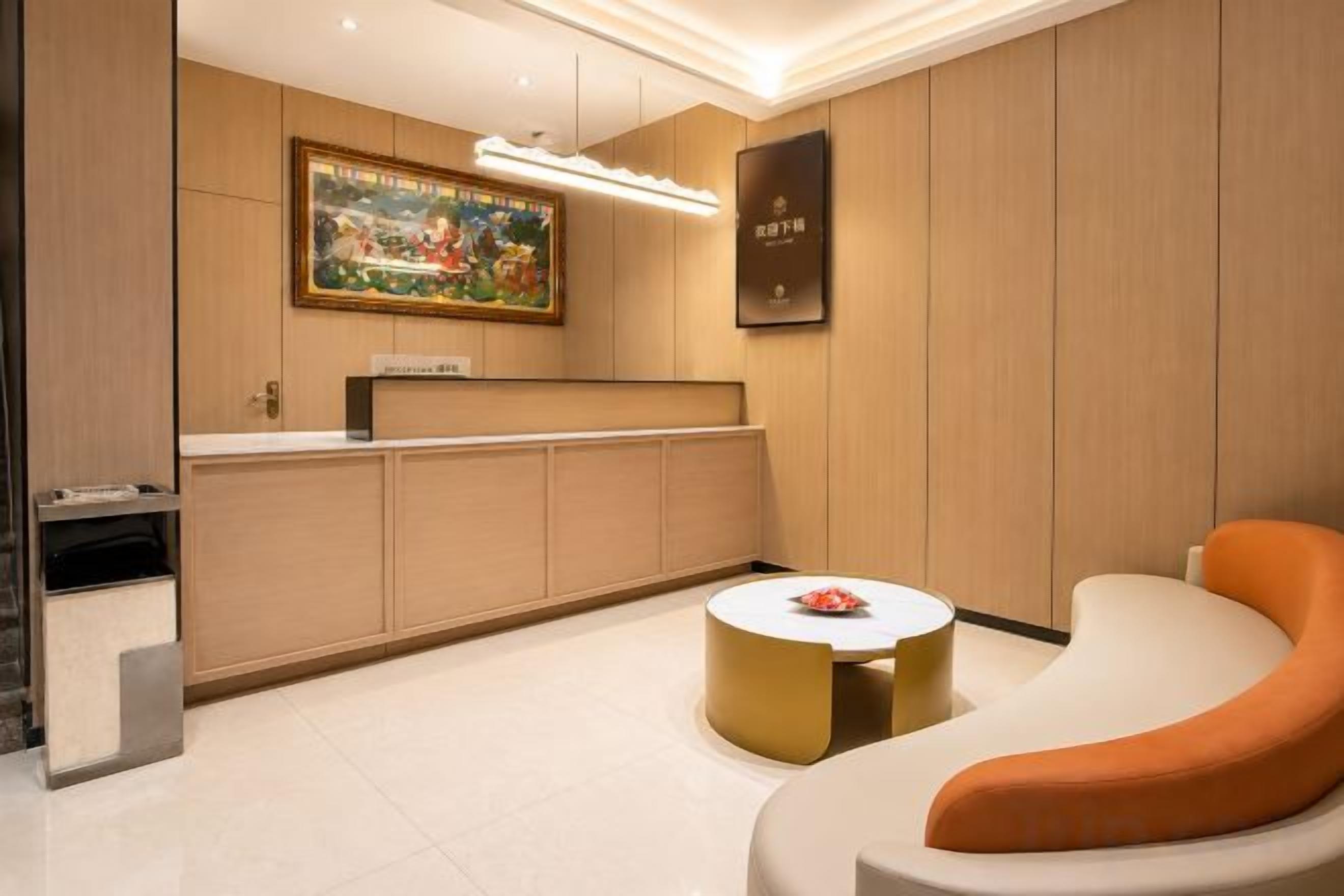 A reception area with a reception desk, a framed painting, and a seating area with a round table and a sofa.