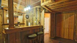 A rustic wooden bar area with stools, a mirror, and a sign reading "BEER". - Carriage House Cabin #1 - Near Three Rivers (Walhonding)