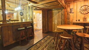A rustic wooden interior with a bar area, stools, and a round table. - Carriage House Cabin #1 - Near Three Rivers (Walhonding)