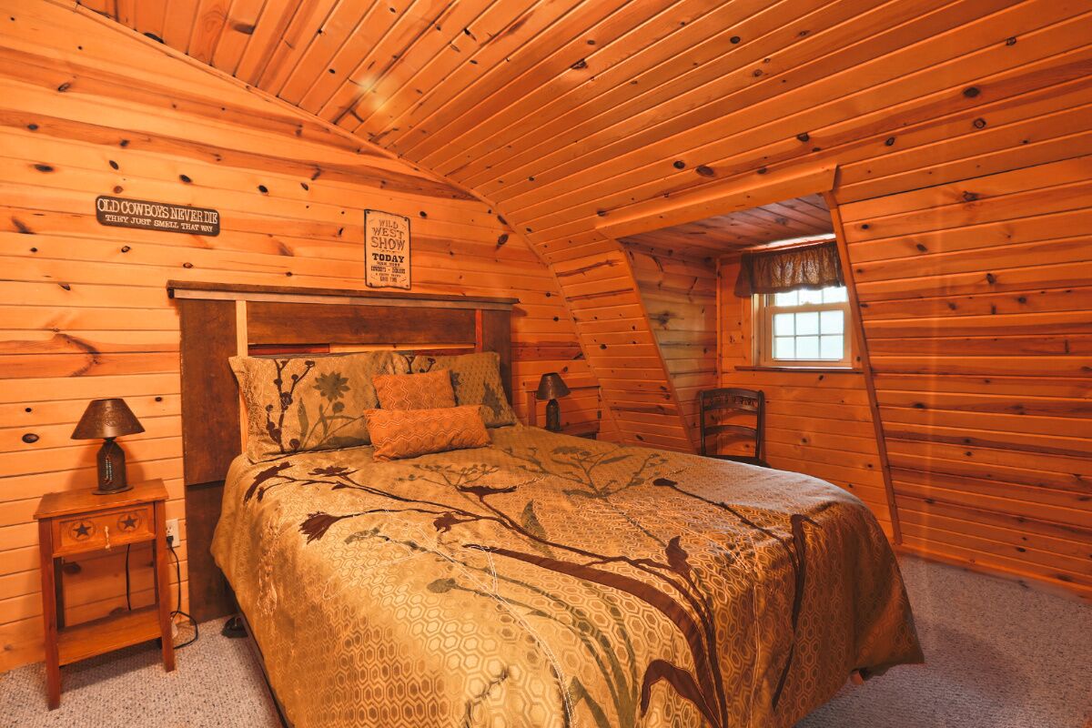 A cozy, log cabin-style bedroom with a bed, a nightstand, and a window.