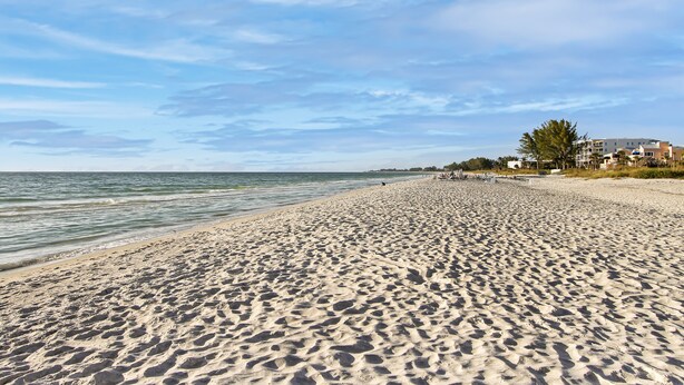 A wide sandy beach with a clear sky and calm sea. - Delightful 2/2 Beach House LBK 5 Min drive to Beach (Longboat Key)