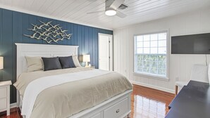 A bedroom with a bed, bedside tables, a desk, a ceiling fan, and a window with blinds. - Delightful 2/2 Beach House LBK 5 Min drive to Beach (Longboat Key)